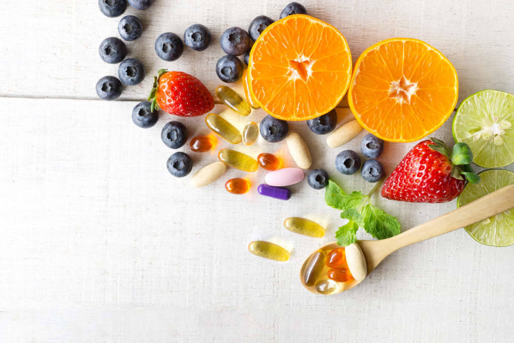 Frutas como laranja, limão, jaboticabas, morangos e cápsulas gelatinosas de suplemento alimentar
