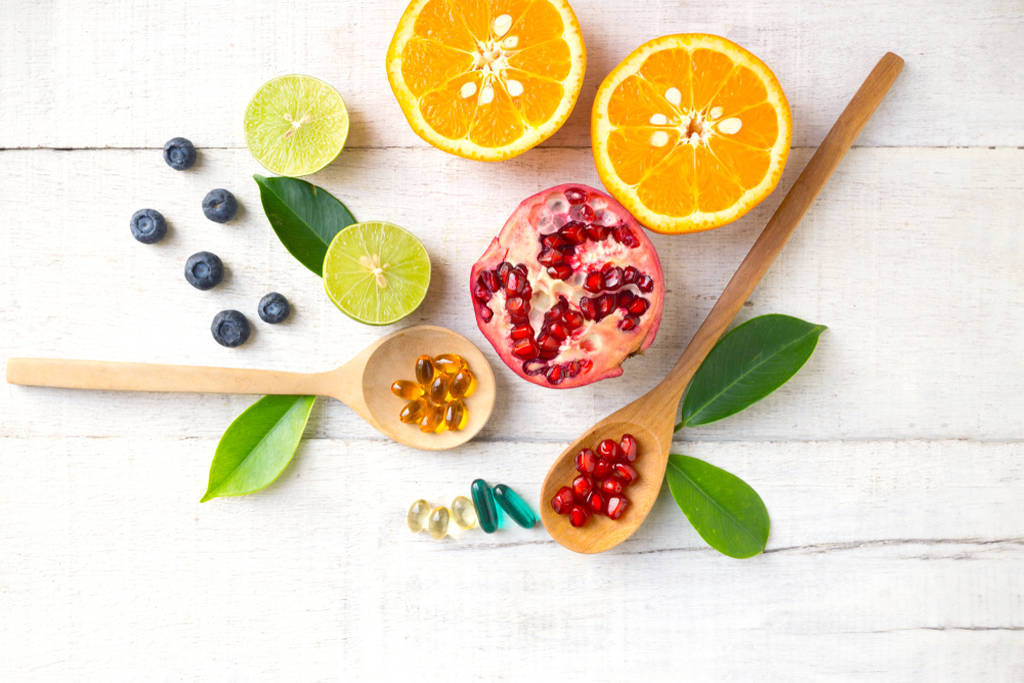Frutas e cápsulas gelatinosas, simbolizando nutrientes e princípio ativo