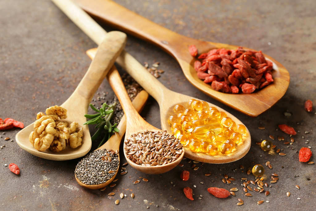 Colheres com nozes, grãos e cápsulas gelatinosas, simbolizando o que é princípio ativo